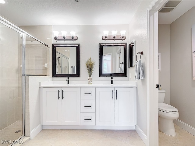 bathroom with vanity, toilet, a shower with shower door, and a textured ceiling