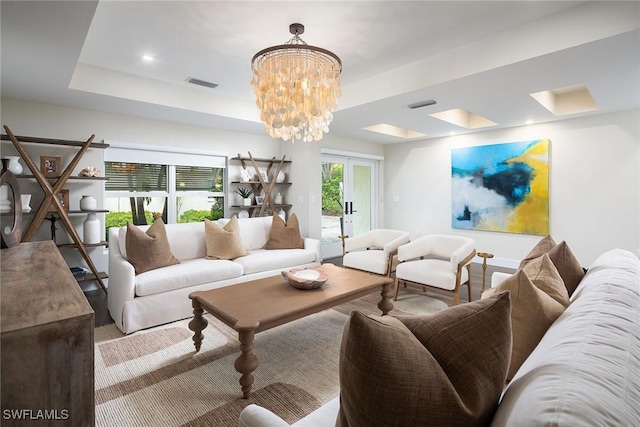 living room featuring a raised ceiling and an inviting chandelier