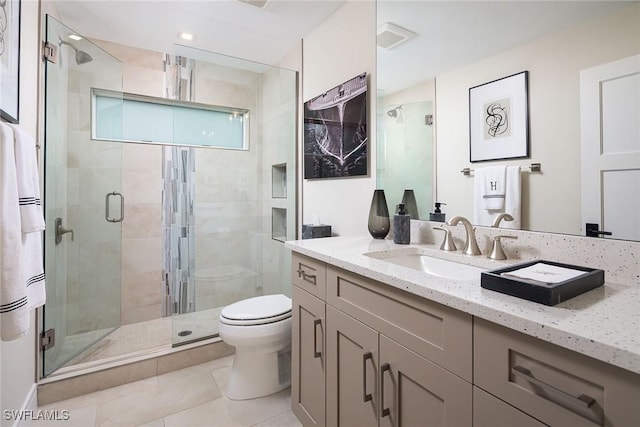 bathroom featuring toilet, vanity, tile patterned floors, and a shower with door