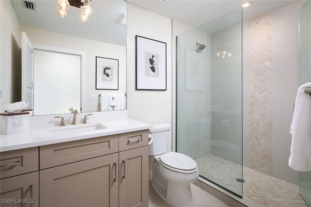 bathroom with a tile shower, vanity, and toilet