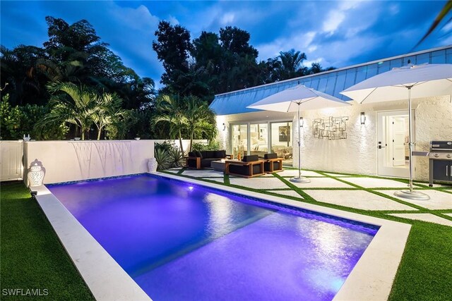 pool at dusk featuring outdoor lounge area, a patio area, and grilling area