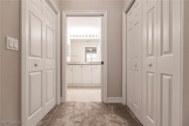 corridor featuring sink and light colored carpet