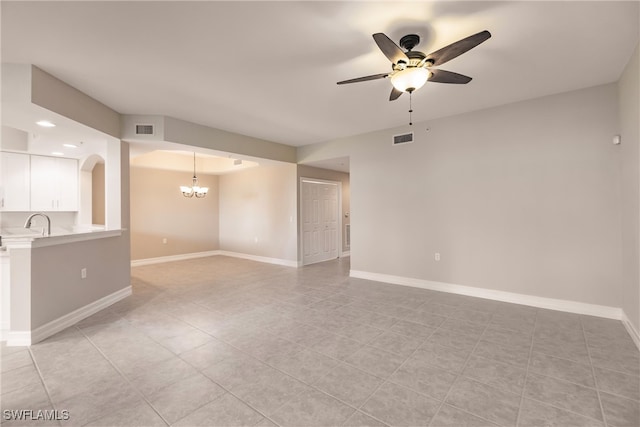 tiled spare room with ceiling fan with notable chandelier