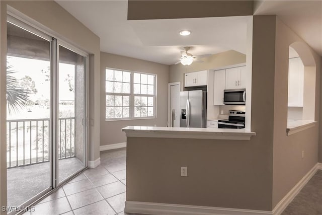 kitchen with ceiling fan, appliances with stainless steel finishes, white cabinetry, light tile patterned flooring, and kitchen peninsula