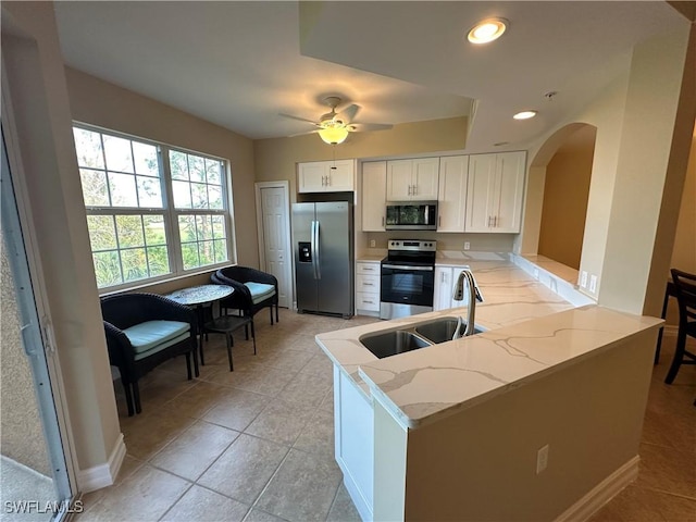 kitchen with sink, appliances with stainless steel finishes, white cabinetry, light stone countertops, and kitchen peninsula