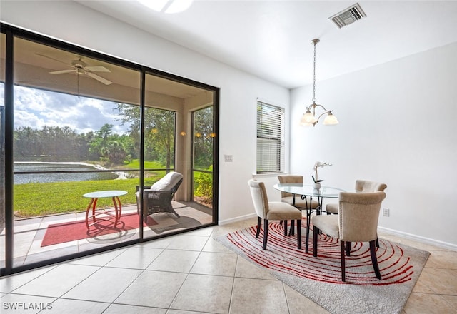 dining area with a water view, light tile patterned flooring, and ceiling fan with notable chandelier