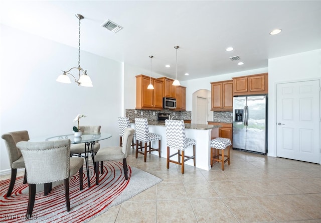 interior space with stone countertops, a kitchen bar, stainless steel appliances, and hanging light fixtures