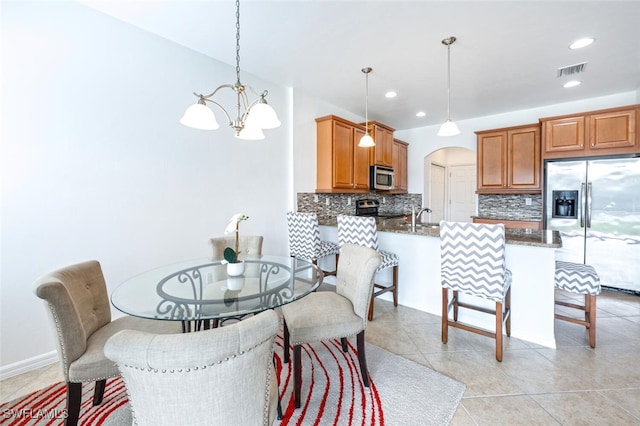 dining space featuring a notable chandelier, light tile patterned floors, and sink