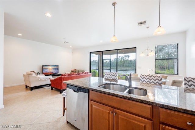 kitchen with dark stone counters, sink, pendant lighting, light tile patterned floors, and dishwasher