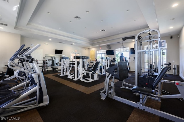 exercise room featuring a raised ceiling and crown molding