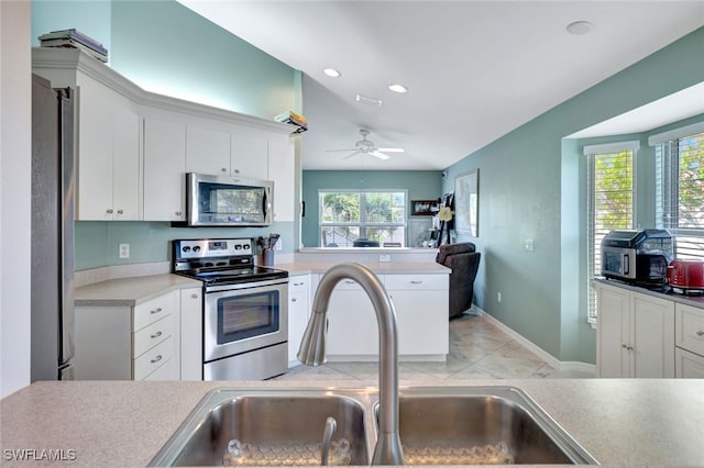 kitchen featuring appliances with stainless steel finishes, white cabinetry, a wealth of natural light, and sink