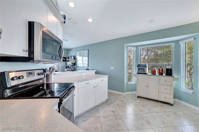 kitchen featuring light tile patterned flooring, white cabinets, stainless steel appliances, and vaulted ceiling