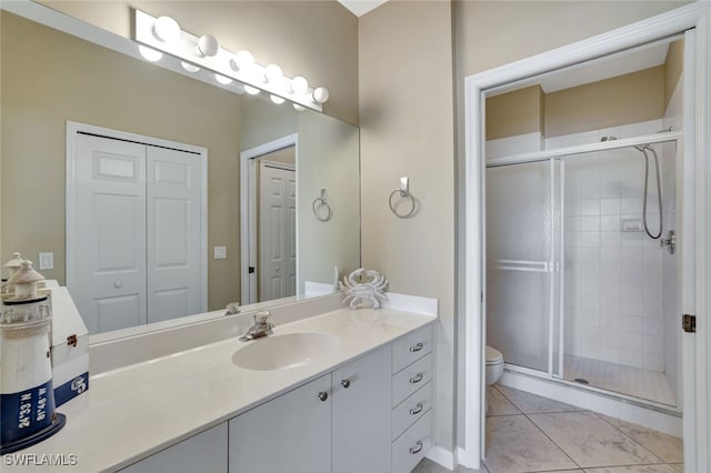 bathroom featuring tile patterned floors, a shower with door, vanity, and toilet