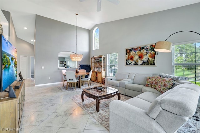 living room featuring ceiling fan with notable chandelier and high vaulted ceiling