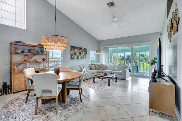 dining space with light tile patterned floors, high vaulted ceiling, and ceiling fan with notable chandelier