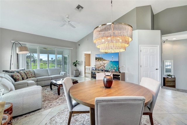 tiled dining space with ceiling fan with notable chandelier and high vaulted ceiling