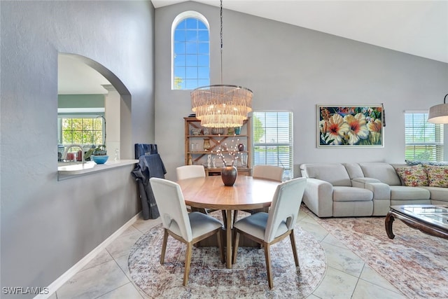 tiled dining space featuring high vaulted ceiling and an inviting chandelier