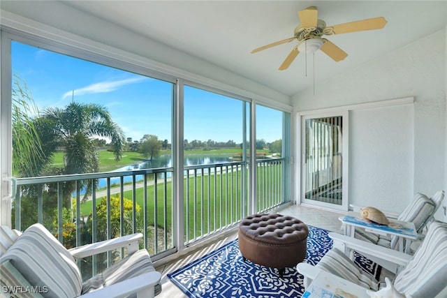 sunroom featuring ceiling fan, a water view, and vaulted ceiling