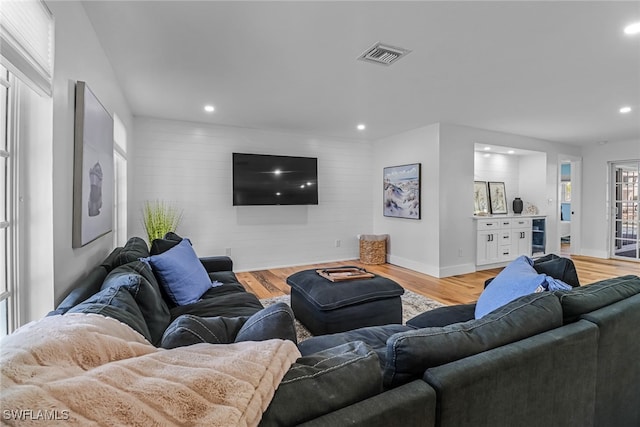 living room featuring visible vents, baseboards, an accent wall, light wood-style floors, and recessed lighting