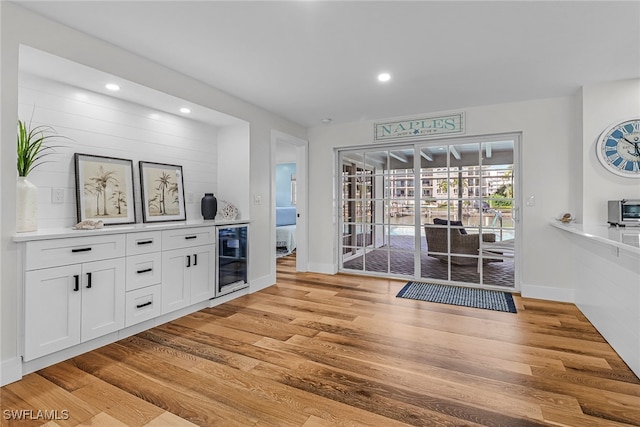 interior space with light wood finished floors, beverage cooler, baseboards, and recessed lighting