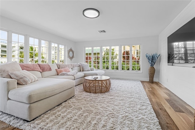 living room with baseboards, visible vents, and wood finished floors
