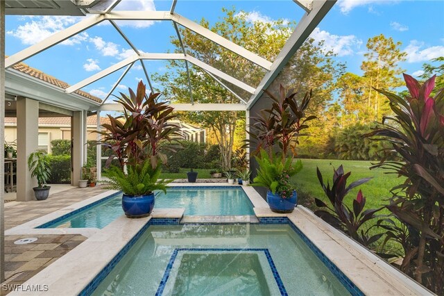 view of pool with glass enclosure, a patio area, a yard, and an in ground hot tub