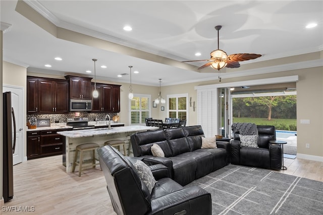 living room with a wealth of natural light, crown molding, and light wood-type flooring