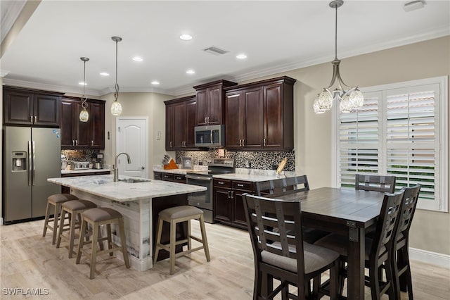 kitchen with ornamental molding, pendant lighting, stainless steel appliances, and sink