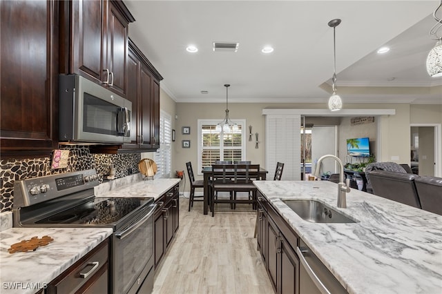 kitchen featuring pendant lighting, sink, ornamental molding, tasteful backsplash, and stainless steel appliances