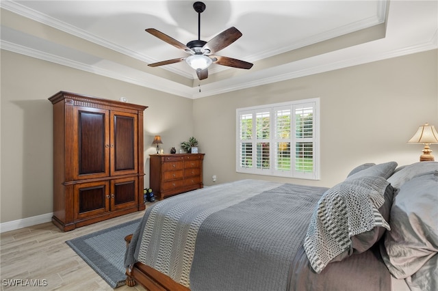 bedroom with a tray ceiling, ceiling fan, ornamental molding, and light hardwood / wood-style floors