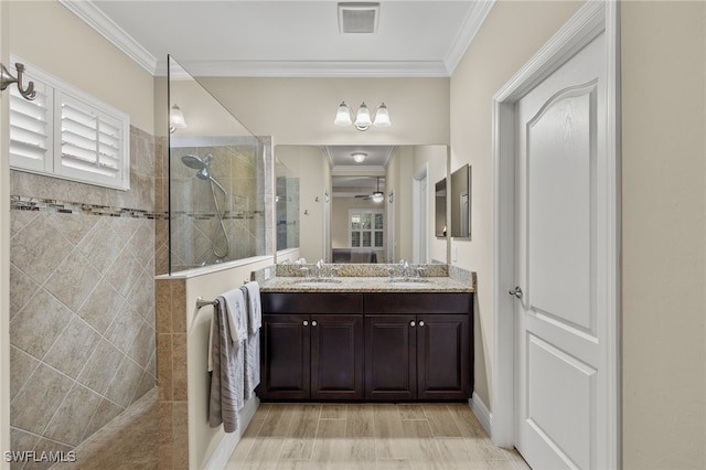 bathroom featuring a tile shower, crown molding, and vanity