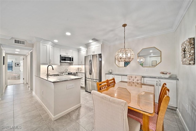 kitchen with kitchen peninsula, stainless steel appliances, sink, white cabinetry, and hanging light fixtures