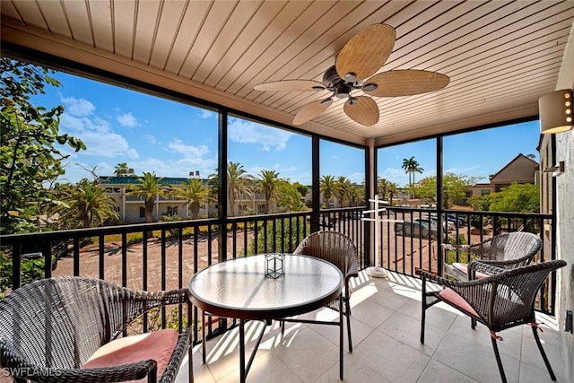 sunroom featuring ceiling fan, wooden ceiling, and a wealth of natural light