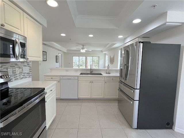 kitchen with sink, tasteful backsplash, crown molding, a tray ceiling, and appliances with stainless steel finishes