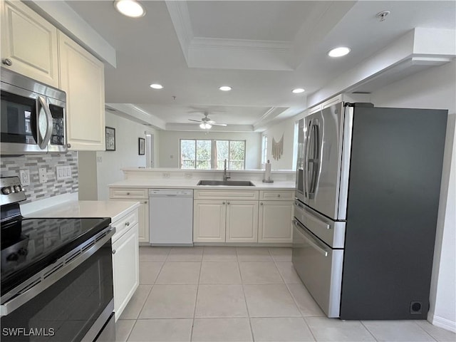 kitchen featuring a sink, light countertops, appliances with stainless steel finishes, and a raised ceiling