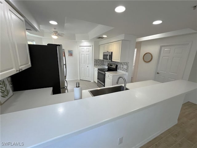 kitchen with stainless steel appliances, light countertops, a peninsula, and white cabinetry