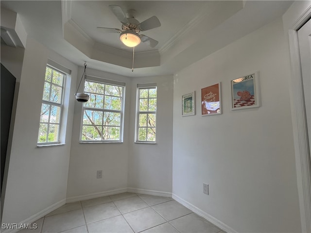 tiled spare room with a healthy amount of sunlight, crown molding, and a tray ceiling