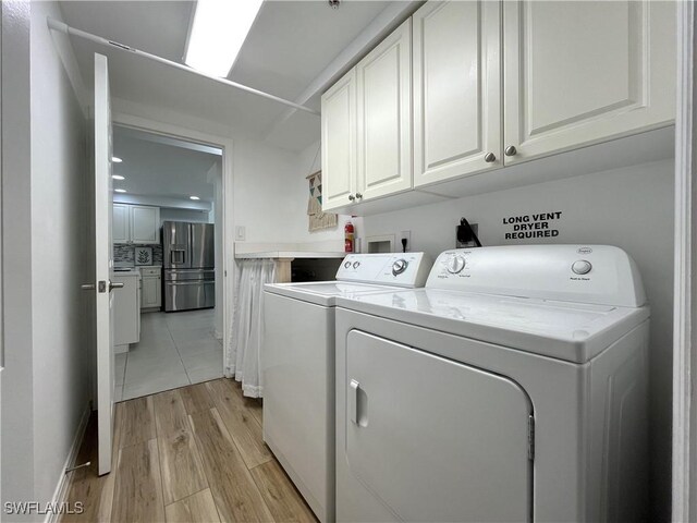 clothes washing area with cabinets, light hardwood / wood-style flooring, and washer and dryer