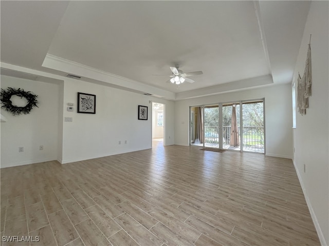 spare room with ceiling fan, a raised ceiling, and light wood-type flooring