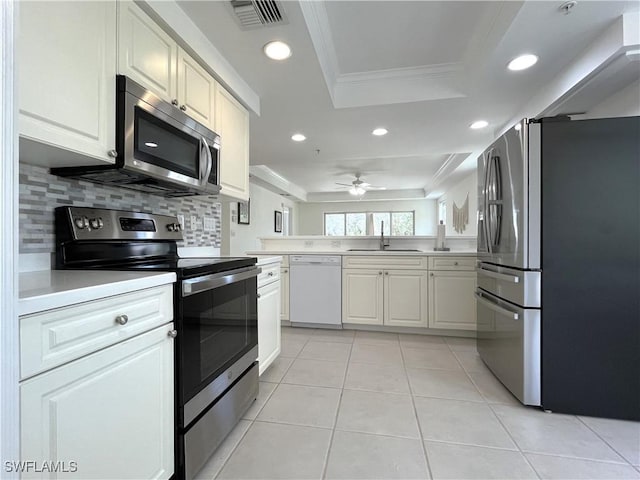 kitchen with visible vents, a raised ceiling, stainless steel appliances, light countertops, and a sink