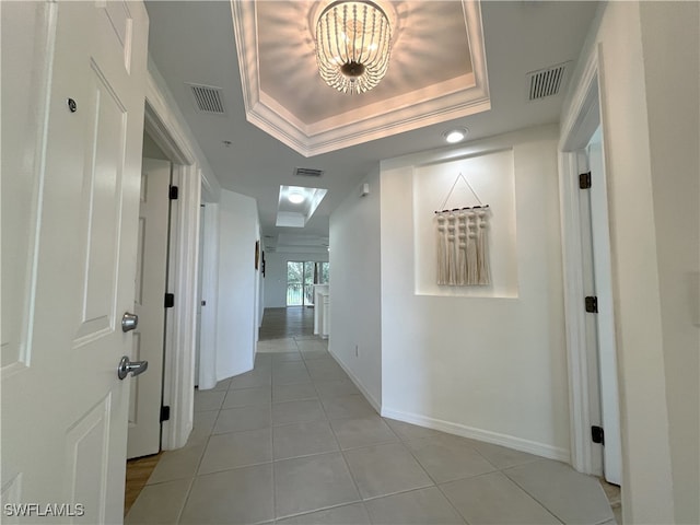 hallway featuring light tile patterned floors, crown molding, and a tray ceiling