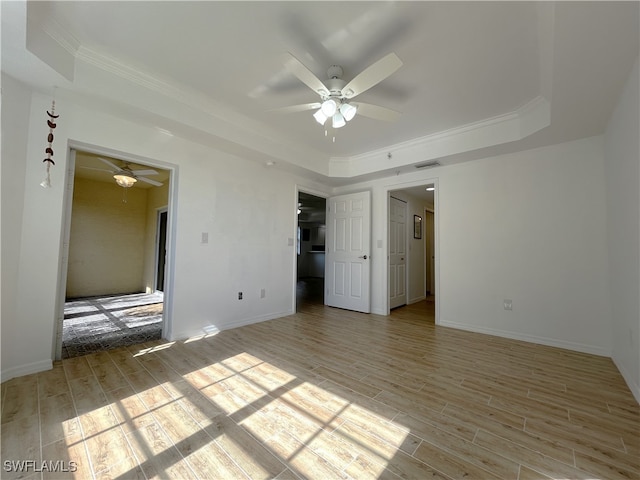 unfurnished bedroom with a tray ceiling, ceiling fan, light hardwood / wood-style floors, and ornamental molding