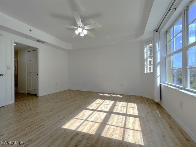 empty room with a wealth of natural light, ceiling fan, ornamental molding, and light wood-type flooring