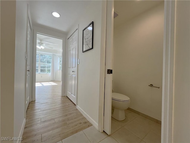 interior space with toilet, ceiling fan, baseboards, and wood finished floors