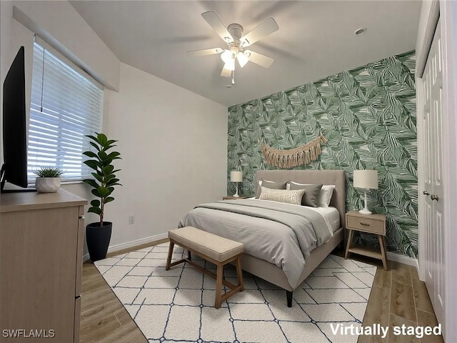 bedroom with wallpapered walls, an accent wall, and baseboards