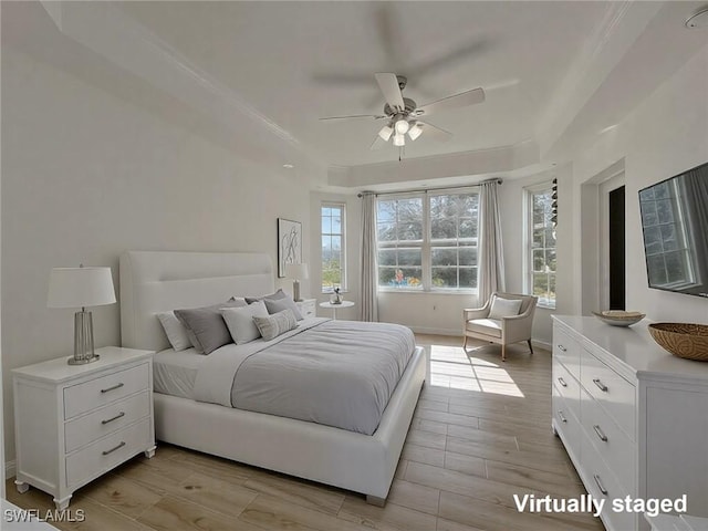 bedroom featuring wood finish floors, a ceiling fan, baseboards, a raised ceiling, and crown molding