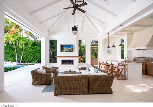 view of patio / terrace featuring ceiling fan, an outdoor kitchen, an outdoor wet bar, an outdoor living space with a fireplace, and grilling area