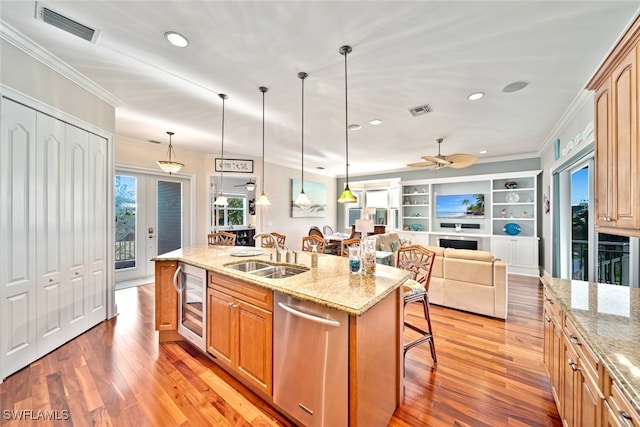 kitchen featuring light stone countertops, sink, light hardwood / wood-style floors, a breakfast bar area, and an island with sink