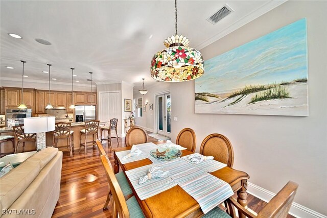 dining room with crown molding and hardwood / wood-style flooring