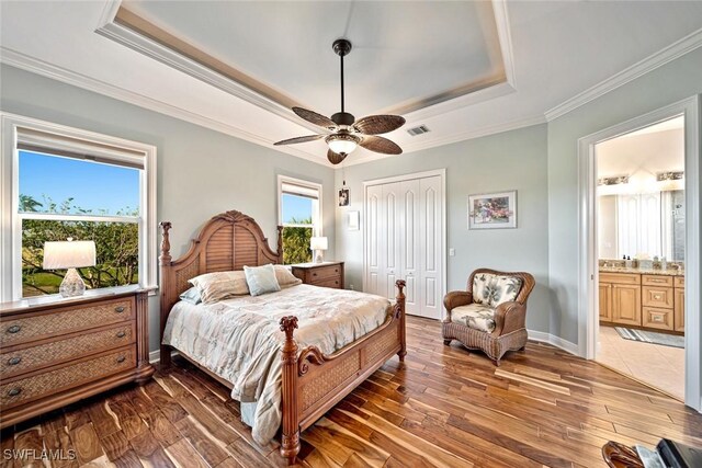 bedroom with multiple windows, ceiling fan, ensuite bathroom, and dark hardwood / wood-style floors